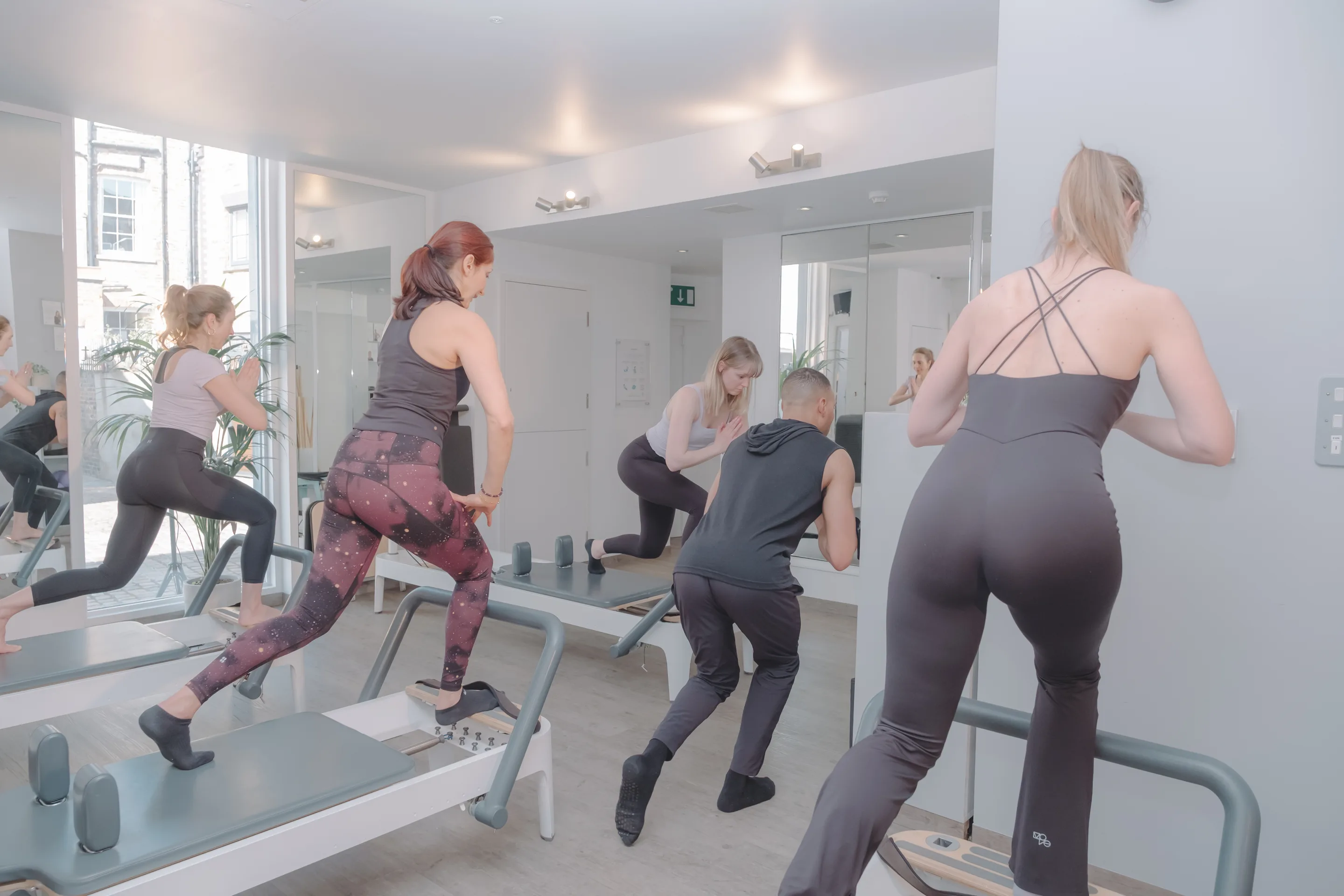 Instructor guiding a member through a Reformer Pilates exercise